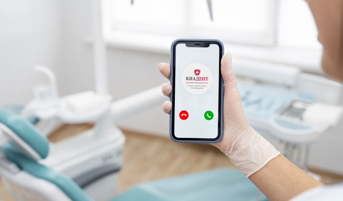 Smartphone with the Kiadent logo in the hand of an assistant in a dental office.